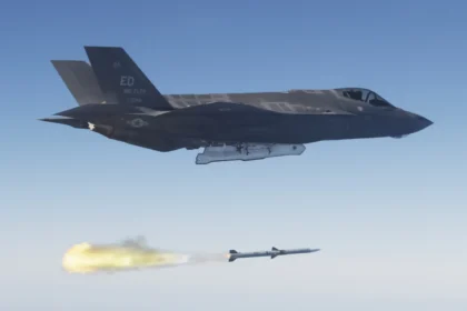 US Air Force F-35A stealth fighter flying above a just-fired AIM-120 AMRAAM missile trailing flame over the Pacific