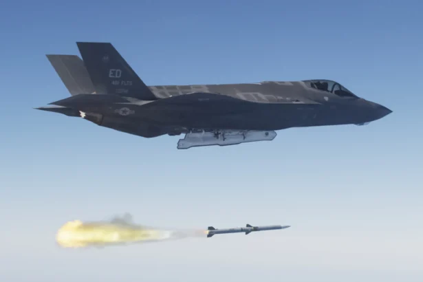 US Air Force F-35A stealth fighter flying above a just-fired AIM-120 AMRAAM missile trailing flame over the Pacific
