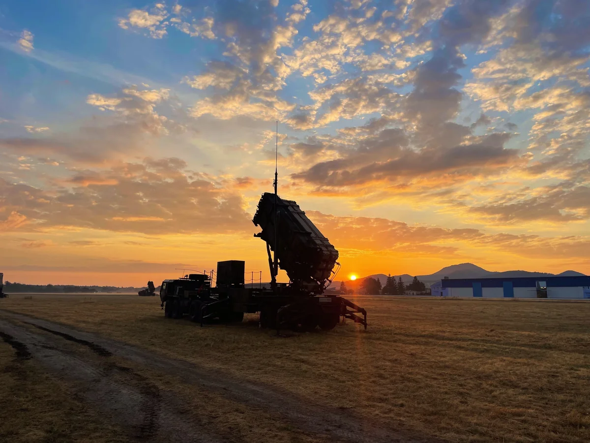 US Army Patriot launcher silhouetted against a sunrise on open ground in Slovakia