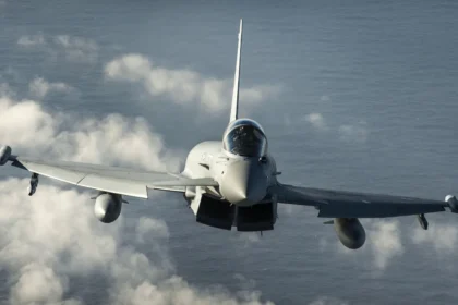 RAF Typhoon fighter jet flying head-on towards the camera above white clouds and the sea