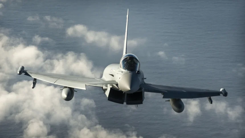 RAF Typhoon fighter jet flying head-on towards the camera above white clouds and the sea