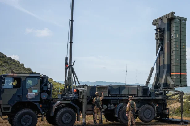Italian Army SAMP/T missile launcher raised upright on a truck, with two soldiers beside it on a Sardinian hillside