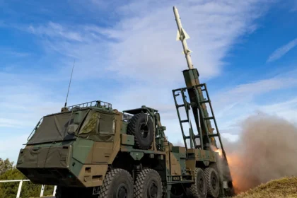A Japanese Type 12 anti-ship missile leaving its truck-mounted launcher on a grassy range under a blue sky